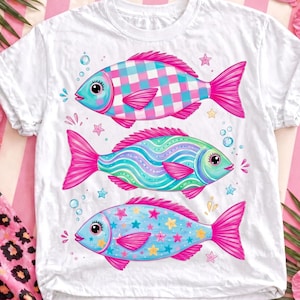 May include: White t-shirt featuring three colorful fish illustrations. Each fish has a unique pattern: a checkered design, wavy lines, and stars. The fish are in shades of blue, green, and pink, with pink fins and tails.