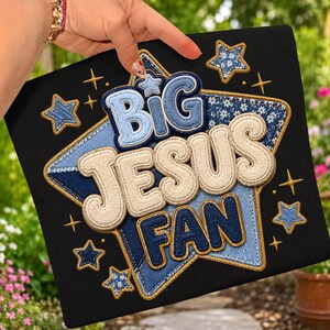 Puede incluir: Un panel de tela negro cuadrado con un gran diseño de estrella bordado con patrones de mezclilla azul y flores. El texto BIG JESUS FAN está aplicado en letras texturizadas y superpuestas en tonos azul claro, crema y azul marino oscuro.
