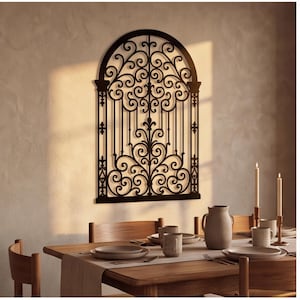 May include: A black metal wall art piece featuring an arched window design with intricate scrollwork, fleur-de-lis accents, and vertical bars. The decorative panel is mounted on a wall above a wooden dining table set with plates and candles.