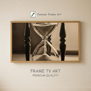 May include: A sepia-toned framed print of an hourglass. The hourglass is centered, with sand flowing from the top to the bottom. The frame is a light brown color. The text "Forever Frame Art" is in the top right corner.