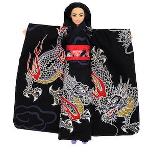May include: A doll wearing a black kimono with a red obi. The kimono features a detailed dragon design in shades of gray, red, and gold. The doll has black hair and is wearing purple shoes. The overall aesthetic is inspired by Japanese culture.