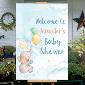 May include: A blue and white baby shower welcome sign with a cartoon elephant holding balloons. The sign says "Welcome to Jennifer's Baby Shower".