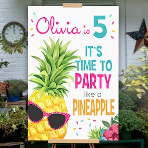 May include: A white sign with a pineapple wearing sunglasses and the text "Olivia is 5 It's time to party like a pineapple".