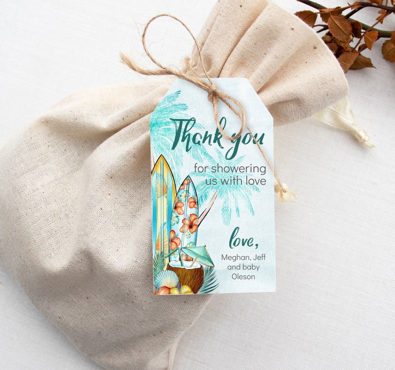Puede incluir: Una bolsa de regalo con una etiqueta que presenta tablas de surf, palmeras y el texto "Thank you for showering us with love". La etiqueta est&aacute; atada con hilo. La bolsa es de tela beige claro.