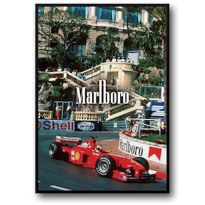 May include: A framed poster featuring a red Formula 1 race car speeding on a track. The poster includes the "Marlboro" logo and a backdrop of a grand building with spectators. "Shell" and "Magneti Marelli" logos are also visible.