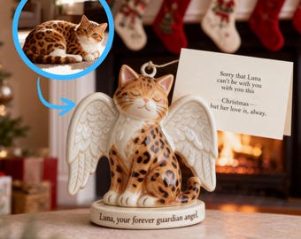 May include: A ceramic cat angel ornament with a spotted coat, white wings, and closed eyes. The ornament has a tag that reads "Sorry that Luna can't be with you with you this Christmas - but her love is, alway." The base reads "Luna, your forever guardian angel."