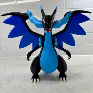 May include: A 3D-printed dragon figurine in black and blue. The dragon has large blue wings, a blue belly, and white claws. The dragon's head is black with red eyes and blue flames. The figurine is a collectible item.