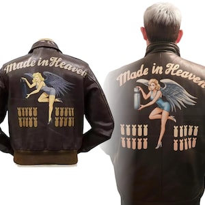 May include: Brown leather jacket with the words "Made in Heaven" and a pin-up girl graphic on the back. The graphic includes a blonde woman with wings and bombs. The jacket has a brown collar and cuffs.