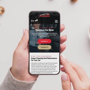 K&ouml;nnte beinhalten: Ein Smartphone zeigt eine Website f&uuml;r Autowaschanlagen, gehalten von einer Person. Der Bildschirm zeigt "Ber&uuml;hrungslose Autow&auml;sche" und "Expertenreinigung und -wartung f&uuml;r Ihr Auto". Das Telefon ist schwarz.