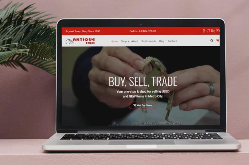 May include: A laptop screen shows an antique store website. The site's headline reads "BUY, SELL, TRADE" and promotes selling USED and NEW items in Metro City. The website's header is red, displaying the store's logo and contact details.