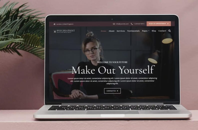 May include: A laptop displays a website for a psychiatrist, featuring a woman in glasses. The site's headline reads "Make Out Yourself." The screen shows a dark background with text and a contact button. The laptop is open on a pink surface.