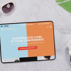 Puede incluir: Una tableta muestra un sitio web de quiropr&aacute;ctica con el texto "Chiropractic Care at Your Convenience". Gafas de sol blancas y auriculares sobre una superficie de m&aacute;rmol.
