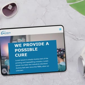 Puede incluir: Una tableta que muestra un sitio web con el texto "WE PROVIDE A POSSIBLE CURE" y el logotipo "MEN'S HEALTH". Gafas de sol y auriculares blancos tambi&eacute;n son visibles en una superficie de m&aacute;rmol.