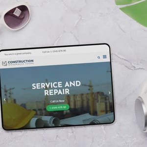 May include: A tablet showing a construction website with the words "SERVICE AND REPAIR". White sunglasses and headphones rest on a marble surface. The website includes a phone number.