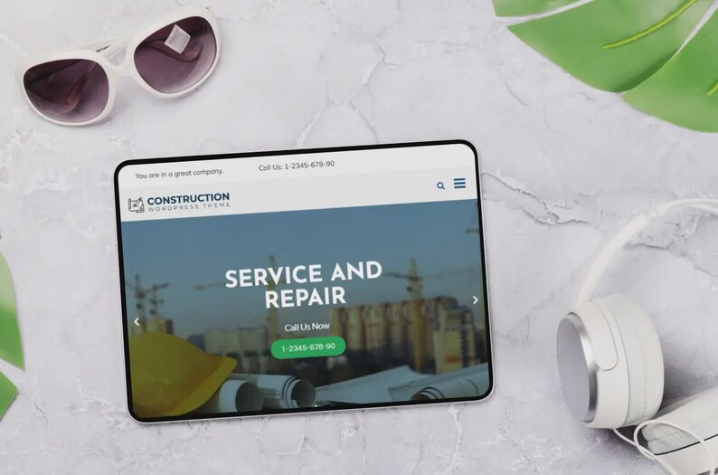 May include: A tablet showing a construction website with the words "SERVICE AND REPAIR". White sunglasses and headphones rest on a marble surface. The website includes a phone number.