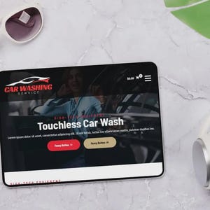 K&ouml;nnte beinhalten: Ein Tablet zeigt eine Website f&uuml;r einen Autowaschservice mit dem Text "Touchless Car Wash". Wei&szlig;e Sonnenbrille, Kopfh&ouml;rer und ein gr&uuml;nes Blatt liegen auf einer Marmoroberfl&auml;che.