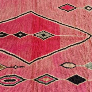 May include: A pink and black geometric rug with a diamond pattern. The rug features a gradient of pink hues, from light to dark, with black zigzag borders and diamond shapes in various colors.