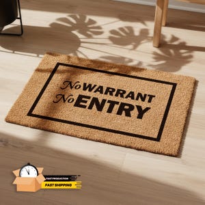 May include: A rectangular doormat made of natural fibers. The mat features a black border and the words "No WARRANT No ENTRY" in black, centered within the border. The mat is placed on a light-colored wooden floor.