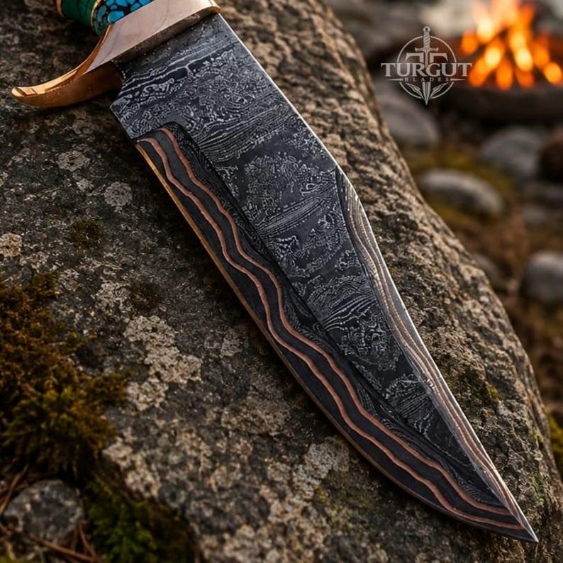 May include: A fixed-blade knife featuring a dark, patterned Damascus steel blade with copper-colored wavy accents along the edge. The handle includes a metallic bolster and a turquoise-colored section. The blade is marked with the Turgut Blades logo.
