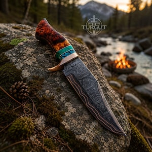 May include: A fixed-blade knife featuring a dark Damascus steel blade with copper accents, a handle made of polished burl wood, and turquoise stone inlays. The blade is marked with the Turgut Blades logo, featuring a sword icon and text.