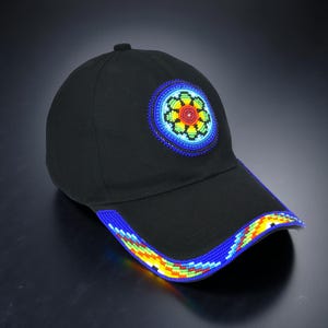 May include: Black baseball cap with a beaded floral design on the front and along the brim. The flower design features red, yellow, green, and blue beads. The brim is outlined with a blue, yellow, and green beaded pattern.