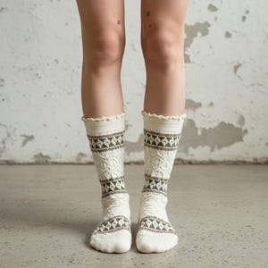 May include: A pair of cream-colored knee-high socks with a textured knit pattern. The socks feature a repeating geometric design in shades of brown and green. The top edge of the socks has a scalloped trim.