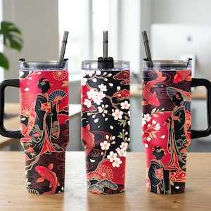 May include: Three stainless steel tumblers with handles and straws, featuring a black and red pattern with illustrations of figures in traditional attire, koi fish, and cherry blossoms. The designs are displayed in a row on a wooden surface.