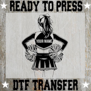 May include: Black and white DTF transfer design featuring a cheerleader with pom-poms. The cheerleader is wearing a uniform with the text "YOUR NAME" on the back. The words "READY TO PRESS" and "DTF TRANSFER" are also displayed.