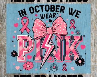 May include: A DTF transfer design with the text "READY TO PRESS" and "DTF TRANSFER". The design features the phrase "IN OCTOBER WE WEAR PINK" in pink, with a large bow, ribbons, and floral accents on a blue background.