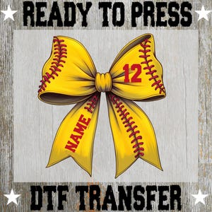 May include: A yellow softball bow design with red stitching and the number 12. The bow has the text "NAME" on one side. The words "READY TO PRESS" and "DTF TRANSFER" are at the top and bottom.