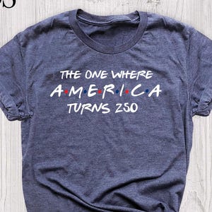 t-shirt with the text "THE ONE WHERE AMERICA TURNS 250" in white, with red and blue accents.