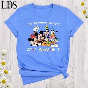 Puede incluir: Camiseta azul claro con un gr&aacute;fico de personajes de Disney, incluyendo Mickey y Minnie Mouse, Goofy, Donald y Daisy Duck, y Pluto. El texto en la camiseta dice "THE ONE WHERE THEY GO TO DISNEY".