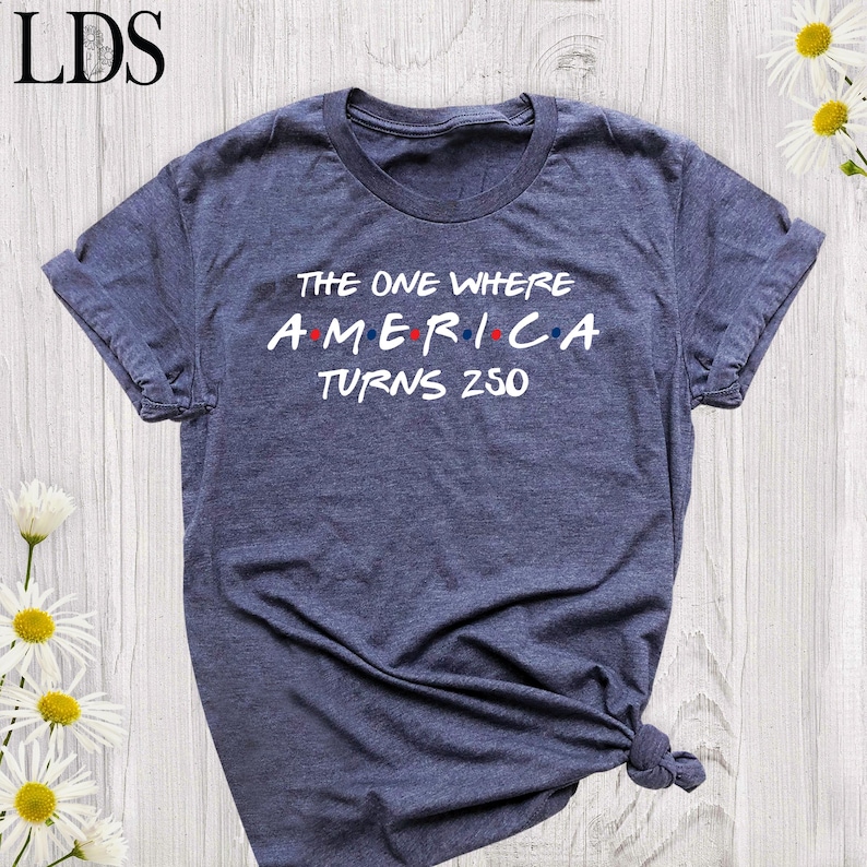 t-shirt with the text "THE ONE WHERE AMERICA TURNS 250" in white, with red and blue accents.