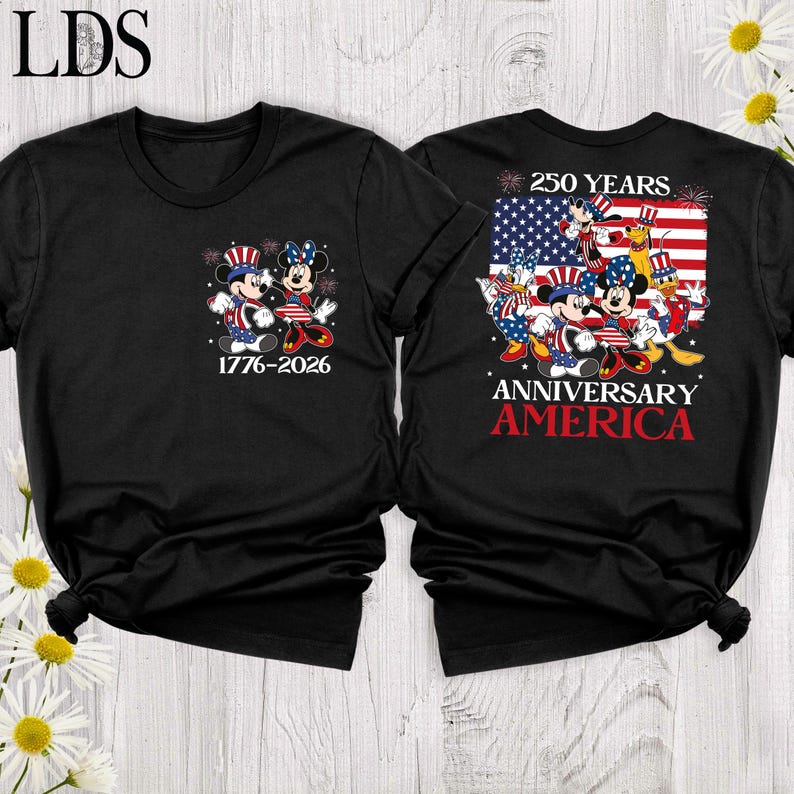 May include: A black t-shirt featuring a front graphic of Mickey and Minnie Mouse in patriotic attire with the text 1776-2026. The back displays a large American flag with Disney characters, the text 250 YEARS ANNIVERSARY AMERICA, and fireworks.