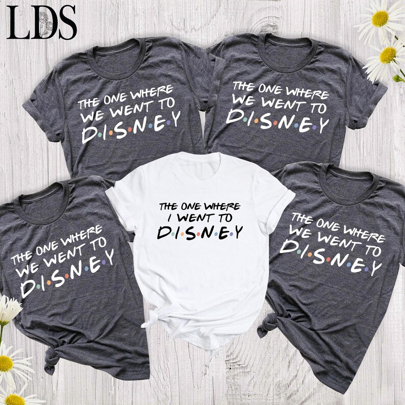 May include: Three dark heather gray t-shirts and one white t-shirt featuring the text "THE ONE WHERE WE WENT TO DISNEY" and "THE ONE WHERE I WENT TO DISNEY" in a bold font, with colorful dots between the letters of the word DISNEY.