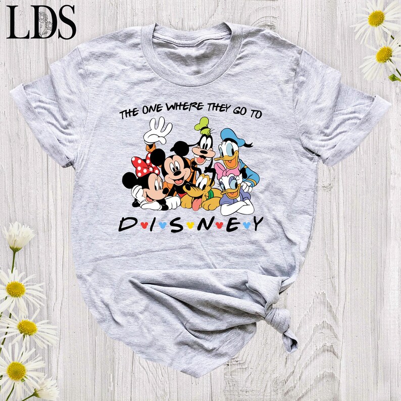 Puede incluir: Camiseta gris claro con un dise&ntilde;o de Disney. El dise&ntilde;o presenta a Mickey y Minnie Mouse, Goofy, Donald y Daisy Duck. El texto dice "The one where they go to Disney" y "Disney" en letras coloridas.