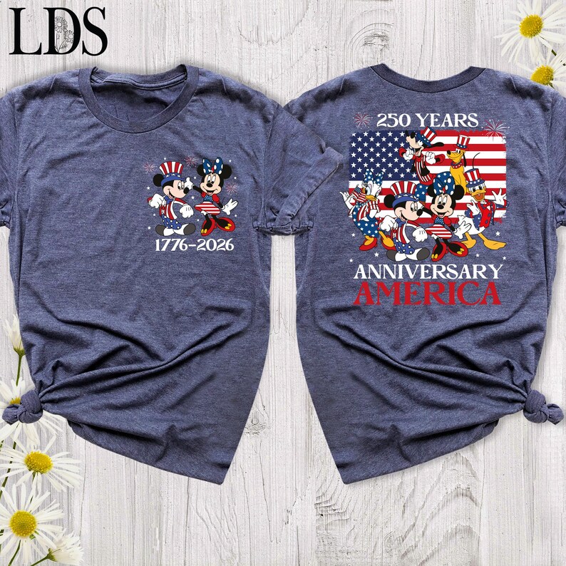 May include: A heathered navy blue t-shirt featuring a small graphic on the front with Mickey and Minnie Mouse in patriotic attire and the text 1776-2026. The back displays a large American flag graphic with Disney characters and the text 250 YEARS ANNIVERSARY AMERICA.