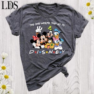 Puede incluir: Camiseta gris oscuro con un dise&ntilde;o de Disney. El dise&ntilde;o presenta a Mickey y Minnie Mouse, Goofy, Donald y Daisy Duck. El texto "THE ONE WHERE THEY GO TO DISNEY" est&aacute; impreso encima de los personajes y "DISNEY" debajo.