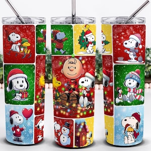 May include: A stainless steel tumbler featuring a festive design with Snoopy and Woodstock in various Christmas scenes. The tumbler has a red, green, and yellow color scheme with a silver straw and lid. The design includes snowflakes and holiday elements.