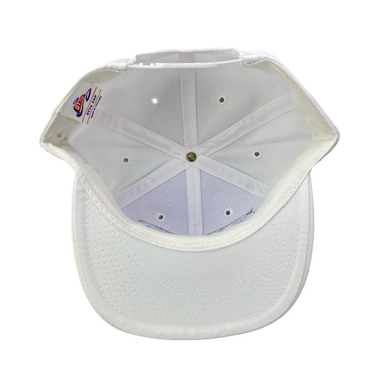 Puede incluir: Gorra de b&eacute;isbol blanca, vista desde el interior, mostrando la construcci&oacute;n interna. La gorra presenta una corona estructurada, una visera curva y un cierre a presi&oacute;n. El interior tiene una banda para el sudor blanca y una etiqueta que dice "OTTO CAP".