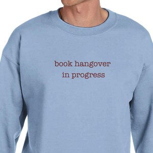 Può includere: Felpa azzurra con la scritta "book hangover in progress" in bordeaux. La felpa ha maniche lunghe e girocollo. Il capo è realizzato in materiale morbido.
