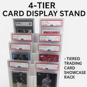 May include: A clear, 4-tier card display stand showcasing graded trading cards. The stand features the text "4-TIER CARD DISPLAY STAND" and "TIERED TRADING CARD SHOWCASE RACK". Each tier holds multiple cards in protective cases.