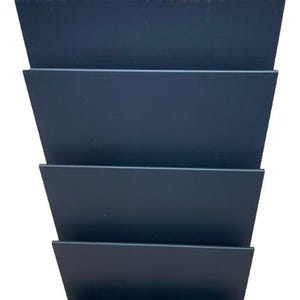 May include: A dark gray, tiered, angled organizer with five horizontal sections. The sections are evenly spaced and create a stepped appearance. The organizer is made of a solid, matte material and is set against a white background.