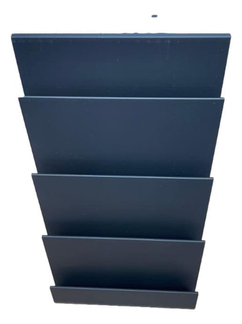 May include: A dark gray, tiered, angled organizer with five horizontal sections. The sections are evenly spaced and create a stepped appearance. The organizer is made of a solid, matte material and is set against a white background.
