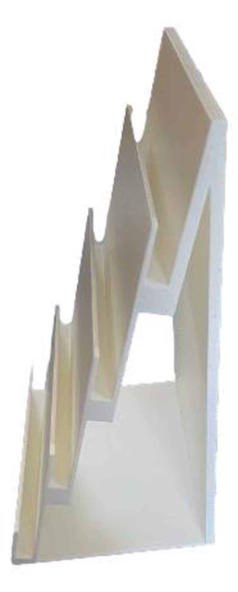 May include: A white, stepped display stand with five angled shelves. The stand has a zig-zag design, with each shelf slightly recessed. The structure is made of a solid, opaque material, and is suitable for displaying various items.