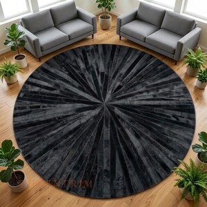 May include: A large, circular area rug featuring a dark charcoal and black colour palette. The rug is constructed from numerous narrow, rectangular panels arranged in a radiating sunburst pattern that extends from the centre to the outer edge.