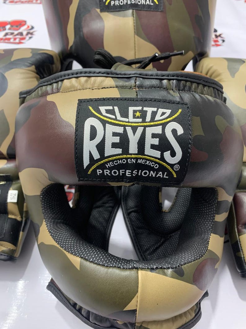 May include: Camouflage boxing headgear and gloves set. The headgear features the "CLETO REYES" logo and the text "HECHO EN MEXICO PROFESIONAL". The set is in shades of brown, green, and black.