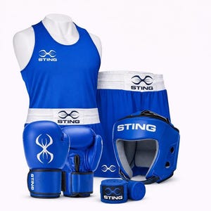 Op de afbeelding: Een blauwe boksset bestaande uit een mouwloos shirt, een short met een witte tailleband, een paar blauwe bokshandschoenen, een blauwe hoofdbeschermer en twee blauwe bandages. Elk item is voorzien van het witte Sting-logo en de merknaam.