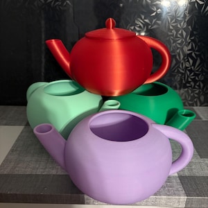 May include: A collection of colorful, spherical teapots in red, green, mint green, and lavender. Each teapot has a rounded body, a curved handle, and a spout. The teapots are arranged in a stack, showcasing their vibrant colors and unique design.
