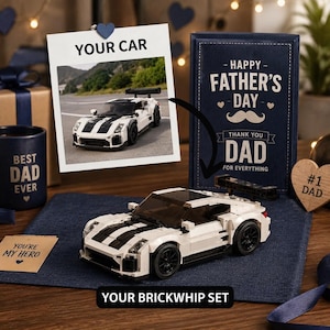 May include: A white and black toy car with a spoiler, displayed with a photo of a similar car. The image includes a Father's Day card, a mug that says "Best Dad Ever", and a wooden heart that says "#1 Dad". The text "Your Brickwhip Set" is also visible.